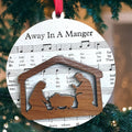 Decorative Christmas ornament with nativity scene and 'Away in a Manger' lyrics on a tree.
